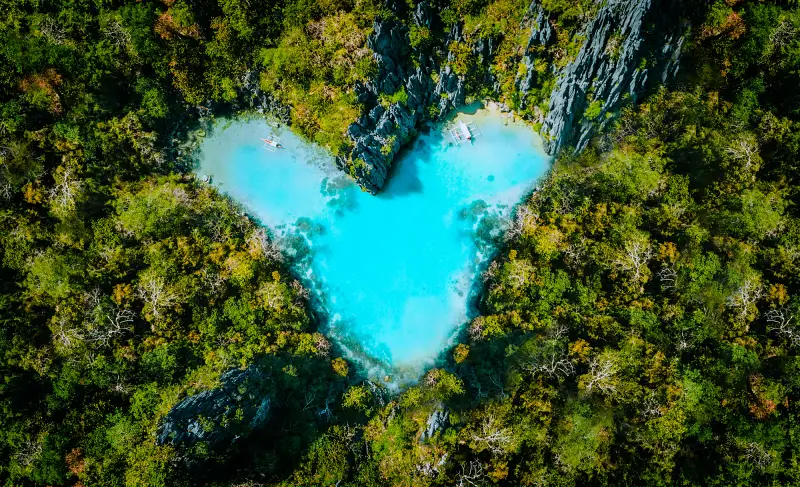 Aerial top view of turquoise lagoon shaped heart inside of tropical island. Love travel summer